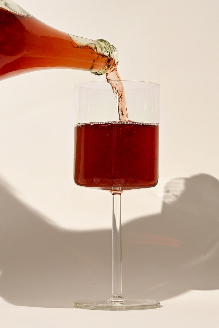 Vertical close-up of Swick Wines 2021 Tempranillo Sparkling Wine deep red wine being poured from bottle into a glass showing rich color and effervescence