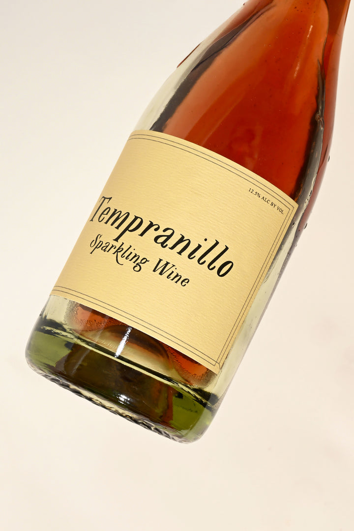Close-up of Swick Wines 2021 Tempranillo Sparkling Wine bottle label with cursive text on cream background showing pink red wine through clear glass