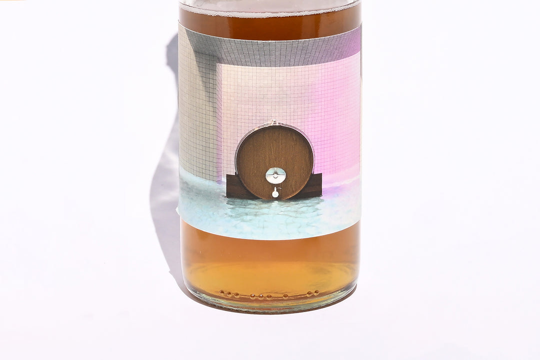 Close-up of Swick Wines 2022 One Foudre bottle label featuring colorful artistic illustration of a wine foudre barrel with pink and teal accents showing amber wine through clear glass
