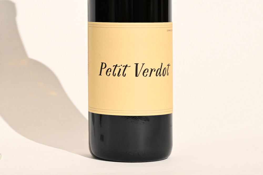 Close-up of Swick Wines 2022 Petit Verdot bottle label with cursive text on cream background and dark green glass