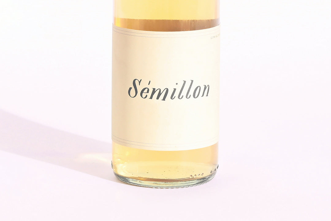 Close-up of Swick Wines 2022 Sémillon bottle label with cursive text on cream background showing golden yellow wine through clear glass
